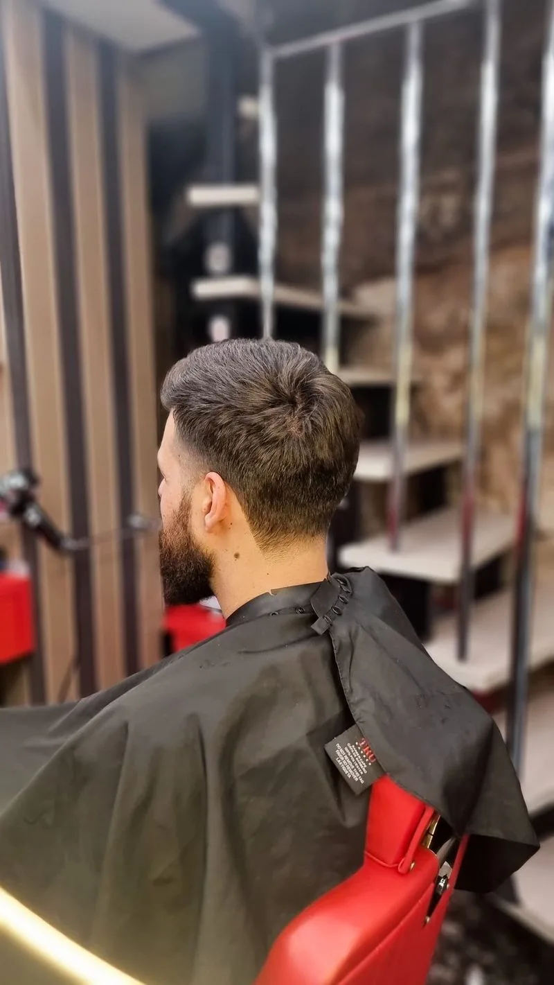 Taglio con sfumatura e barba, visto di spalle in poltrona
